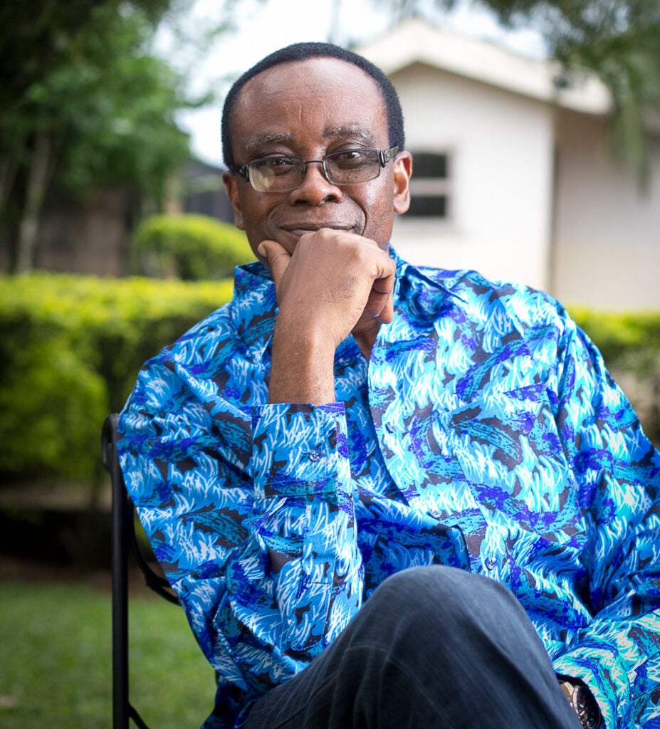 Photo of Nnimmo Bassey, environmental leader, architect, and poet. Bassey is wearing a blue shirt and seated outdoors.